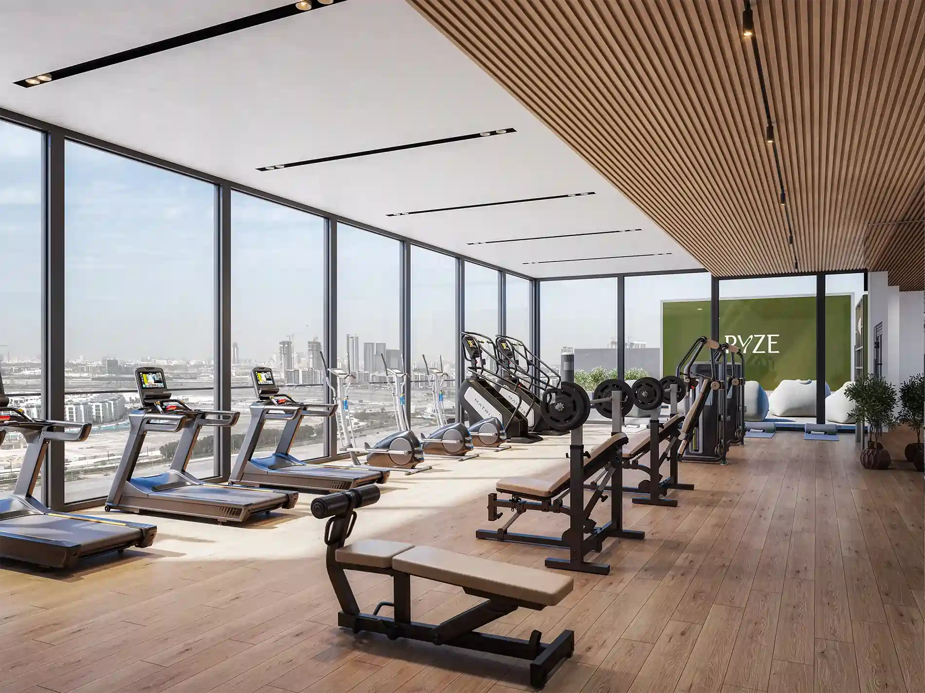 Bright gym overlooking city skyline with treadmills, ellipticals, and weight machines along large windows.