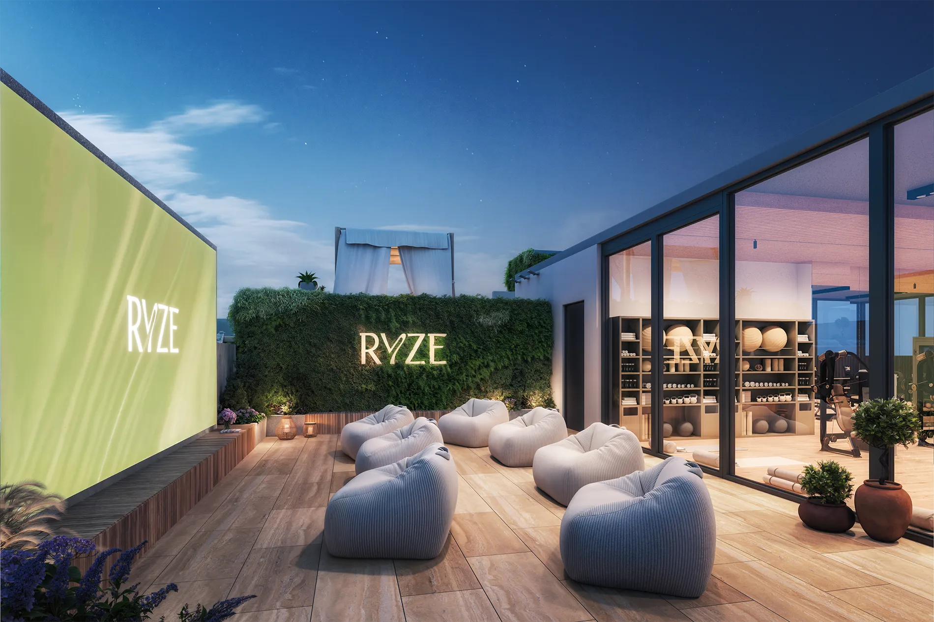 Outdoor lounge area with large bean bags, wooden deck, and glass-walled showroom labeled 'RVZE' against a twilight sky.